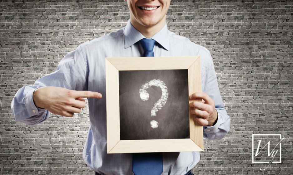 A man in a dress shirt holding a chalkboard with a question mark to represent WarmlyYours radiant heating information.