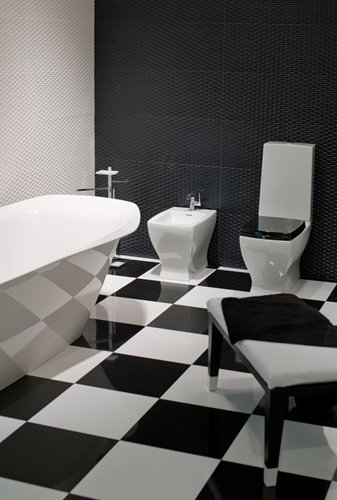 A modern bathroom featuring a bold black-and-white checkerboard floor, a freestanding geometric bathtub, and contemporary white fixtures.