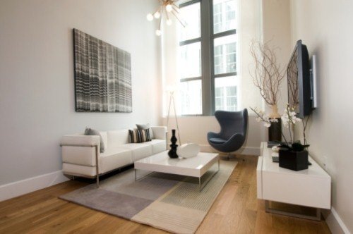 A modern living room with hardwood floors, white sofa, and abstract art, styled for a cozy winter atmosphere.