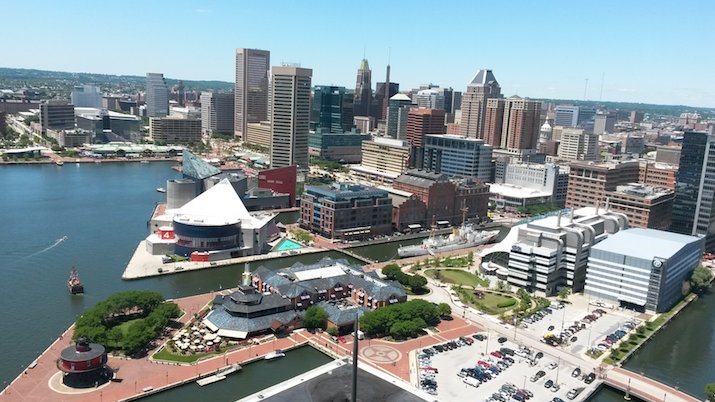 Aerial view of the Baltimore Inner Harbor skyline featuring the National Aquarium, historic piers, and surrounding high-rise buildings.