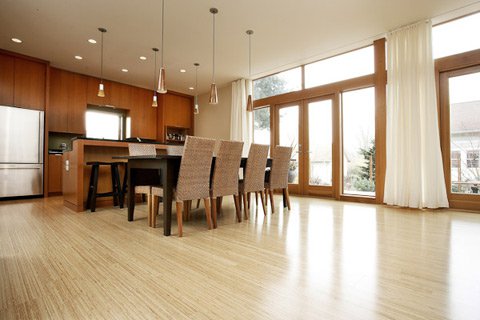 A modern open-concept kitchen and dining area featuring bamboo hardwood flooring installed over an electric radiant floor heating system.