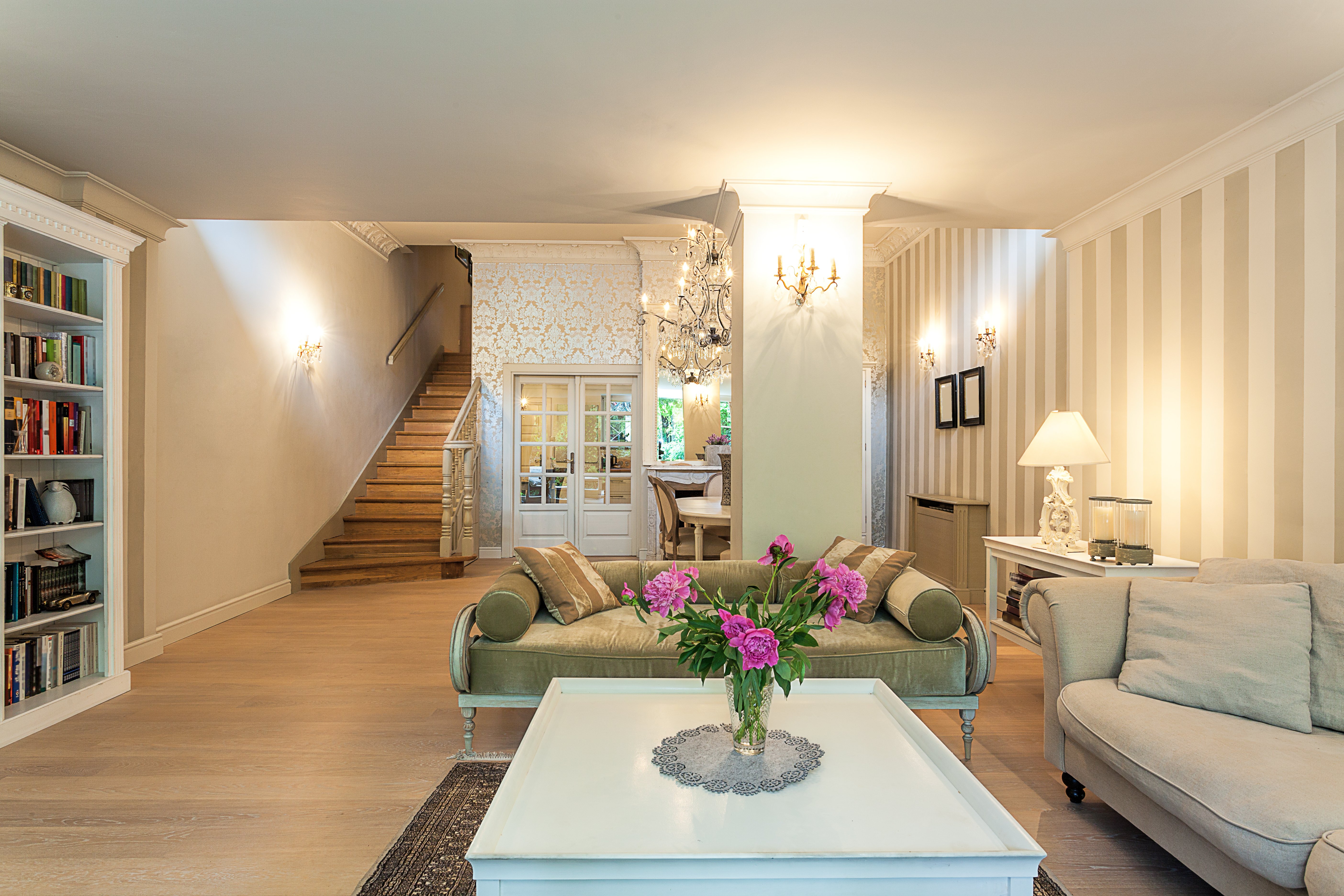 A bright, elegantly decorated basement living room featuring light wood plank flooring and comfortable seating.