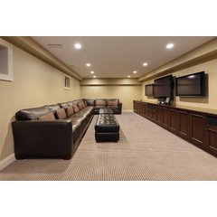A finished basement media room featuring a leather sectional sofa and media console installed over a carpeted floor.