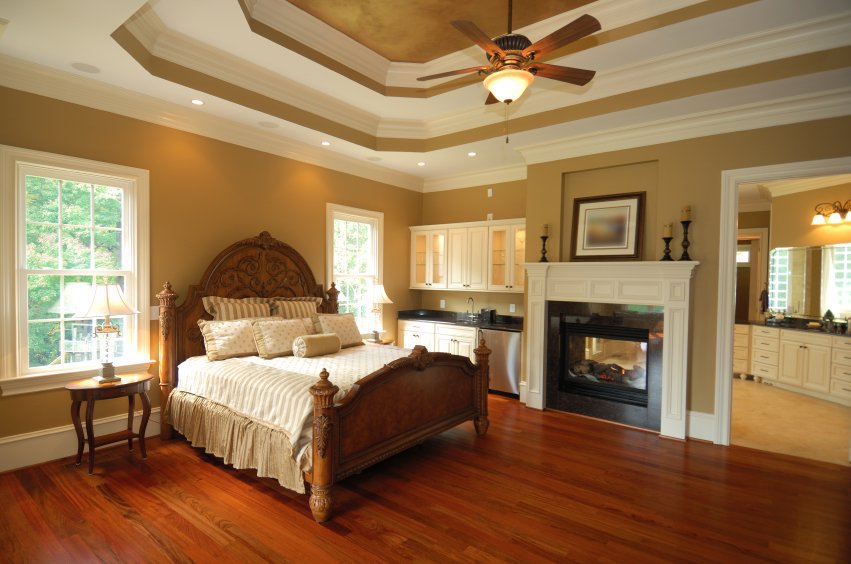 A spacious master bedroom suite featuring polished hardwood flooring and a fireplace, highlighting a comfortable and warm living environment.