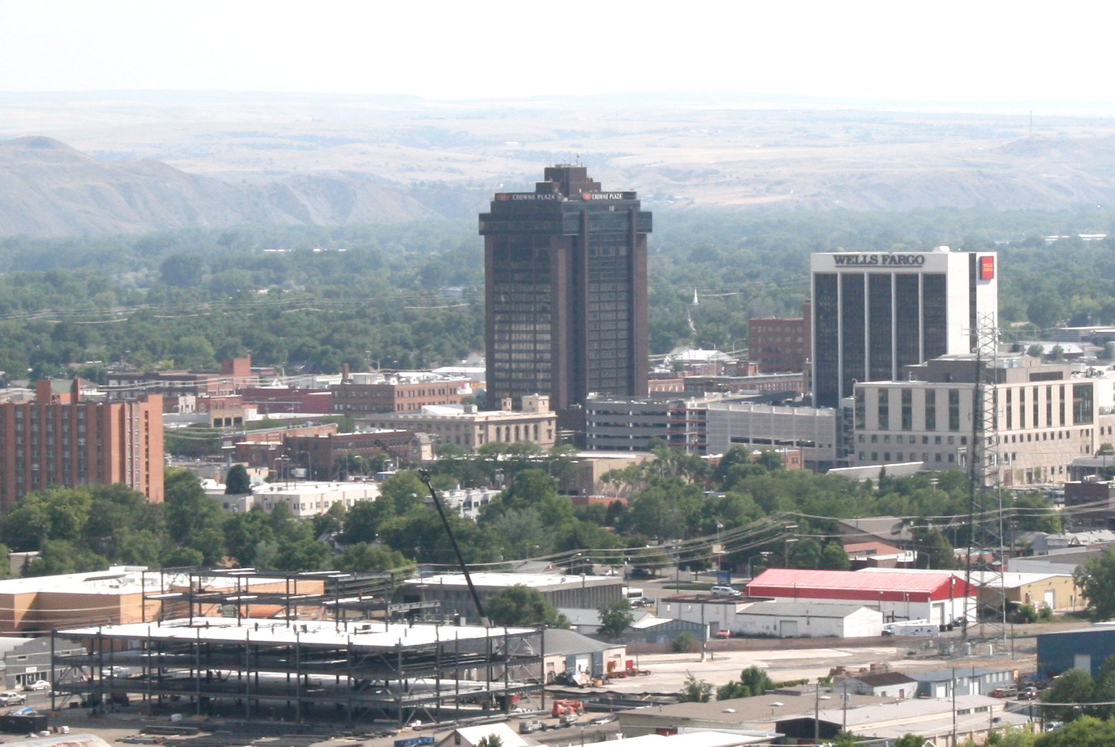 Construction site of a steel building frame in the foreground of the Billings Montana skyline featuring the Crowne Plaza and Wells Fargo buildings.