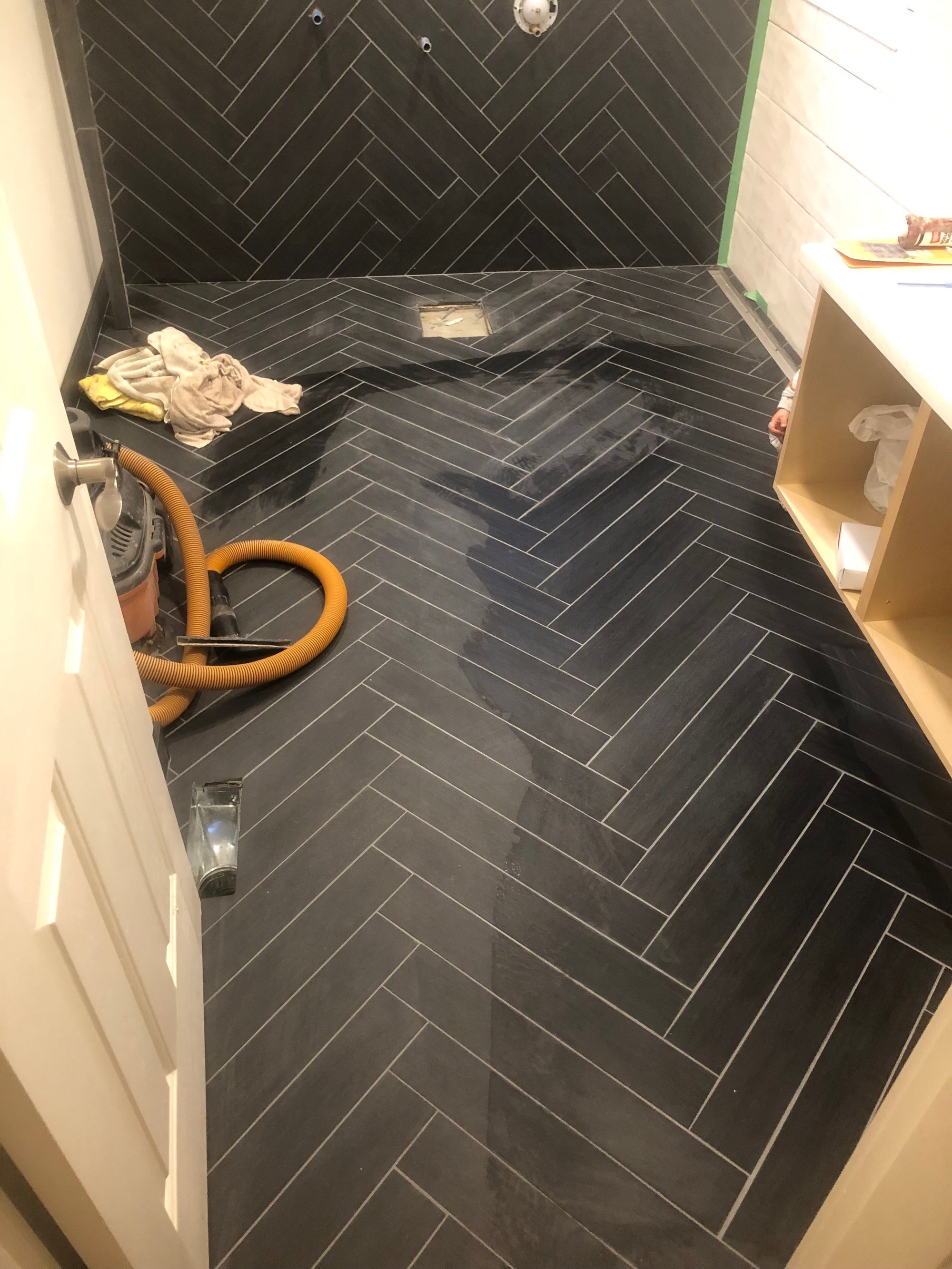 Black tile herringbone floor installed over floor heating system