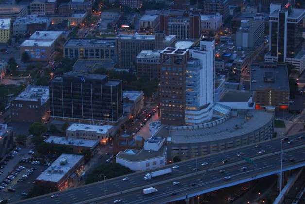 Aerial dusk view of the Bridgeport, Connecticut skyline featuring illuminated city streets and an elevated highway with traffic.