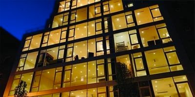 Exterior evening view of the LUX 74 residential building in New York featuring modern geometric architecture and illuminated glass facades.