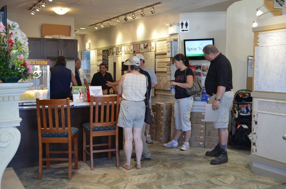 Customers and staff gathered in the City Tile showroom featuring stone-look tile flooring and wall-mounted tile sample displays.