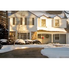 A residential driveway with a snow melting system keeping the asphalt surface clear of snow while surrounding areas remain covered in winter snow.