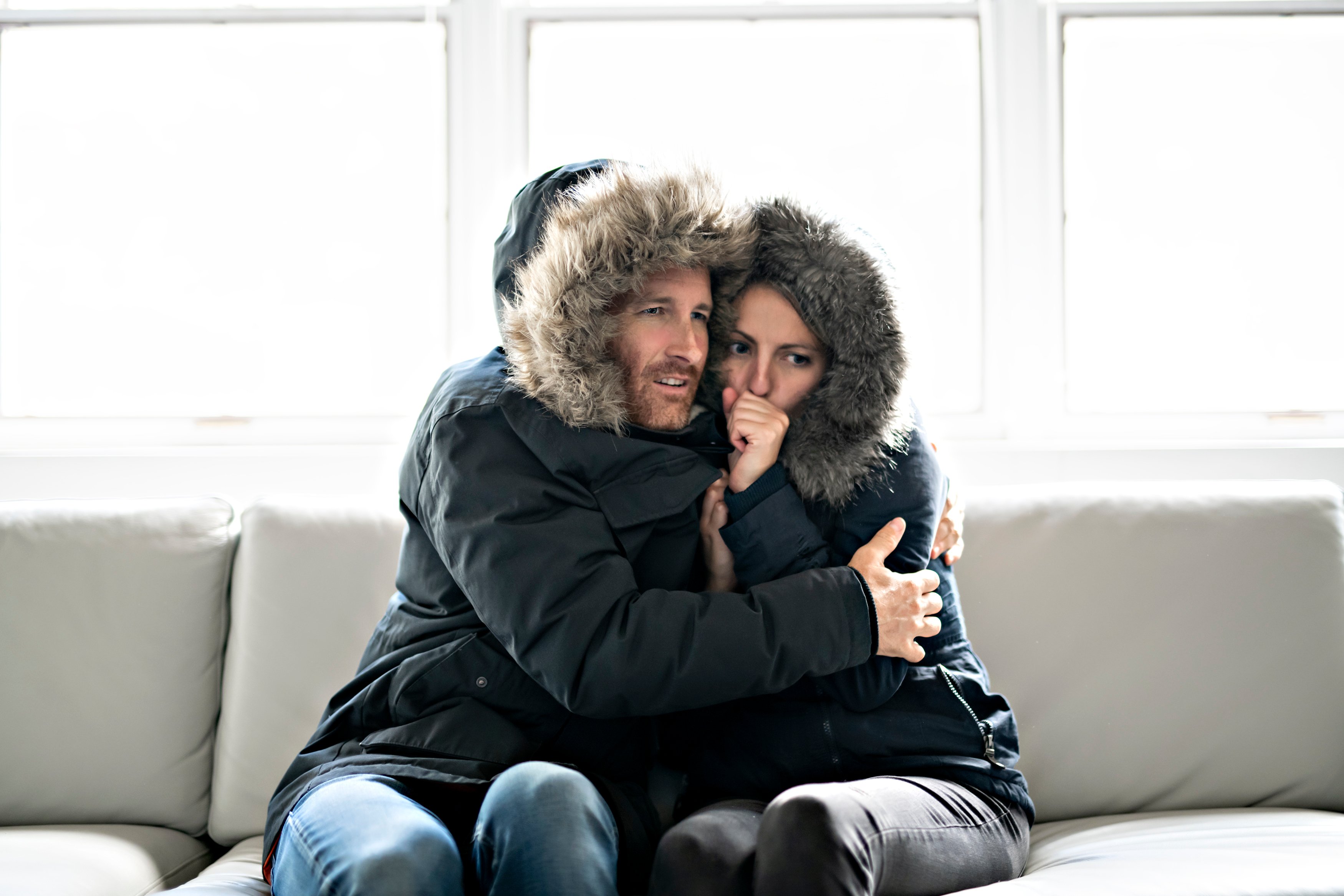 Couple have cold on the sofa at home with winter coat
