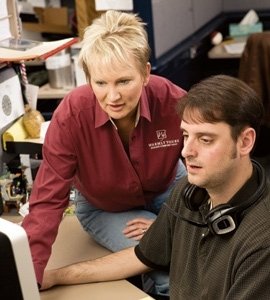 WarmlyYours president Julia Billen collaborating with a colleague at an office desk in front of a computer screen.