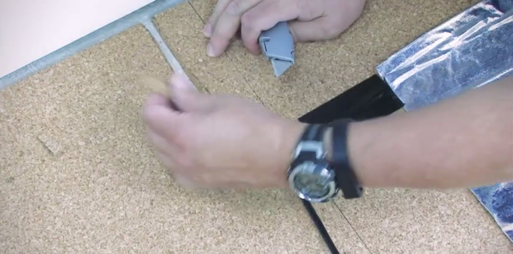 A utility knife cutting a channel in cork underlayment for an Environ electric radiant floor heating mat cold lead.
