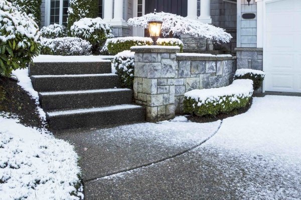 Decorative concrete stairs and driveway with snow