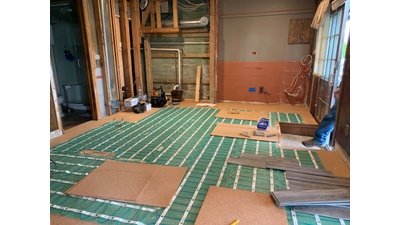 Electric floor heating rolls being installed with cork underlayment in basement remodel