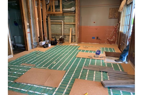 Electric floor heating rolls being installed with cork underlayment in basement remodel