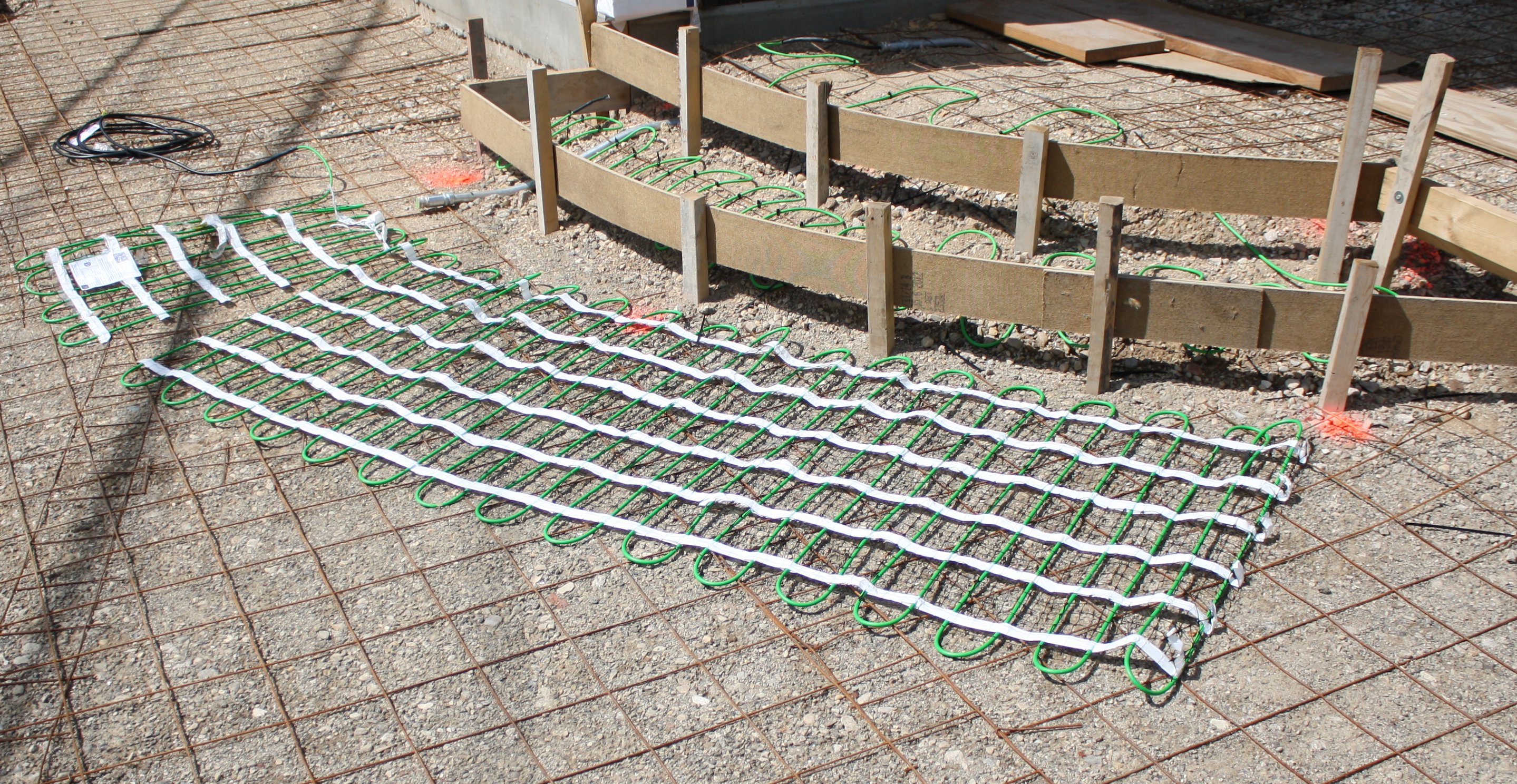Electric snow melting mats being dry-fitted before they're embedded in a heated concrete patio