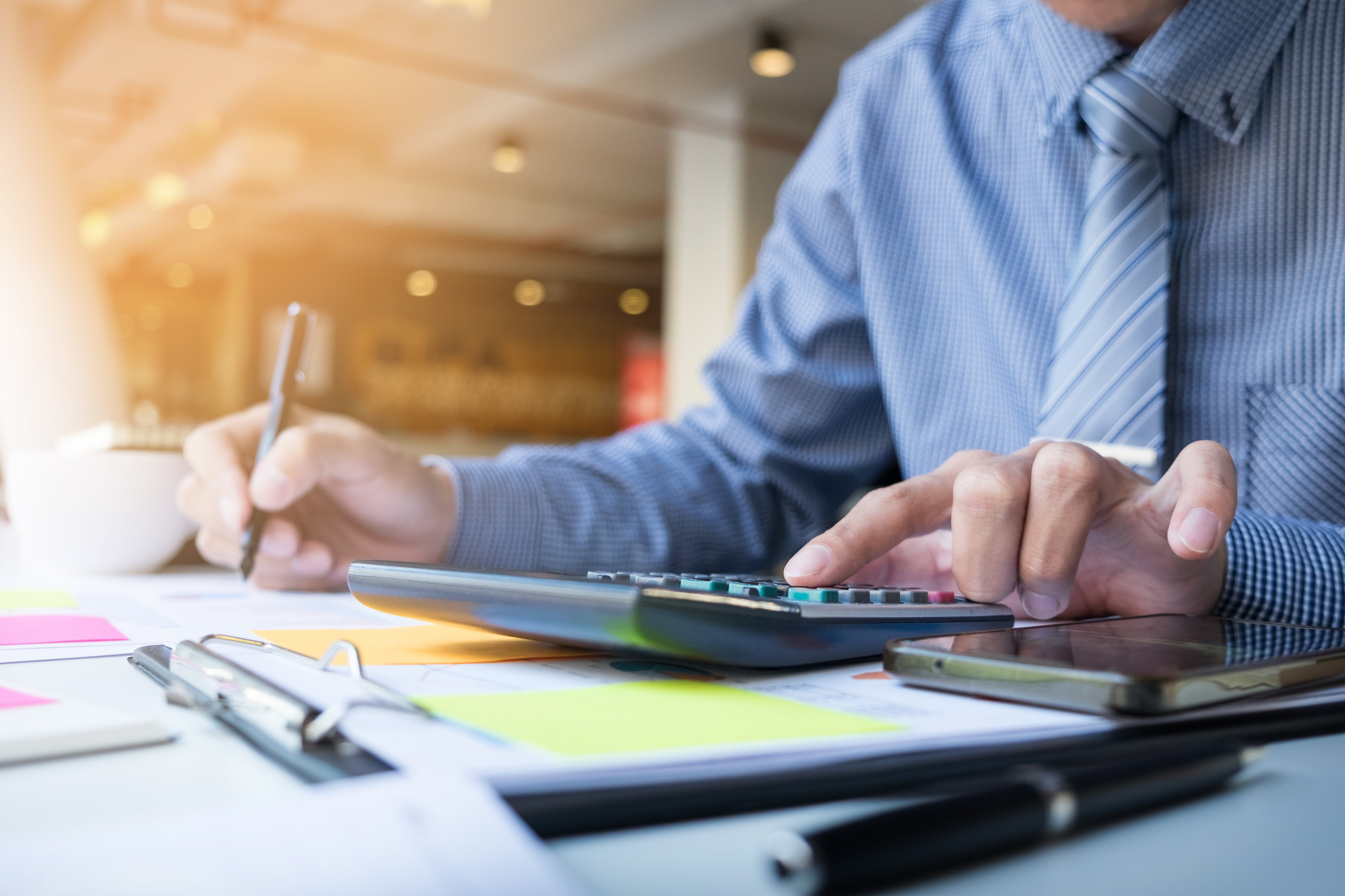 A person using an energy use calculator at a desk with documents and office supplies.