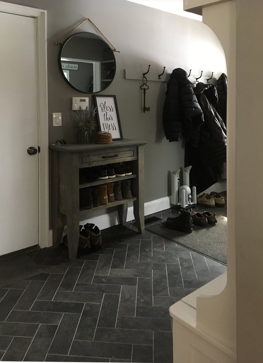 Entryway mudroom with heated tile herringbone floors viewed from a secondary structural hallway angle.
