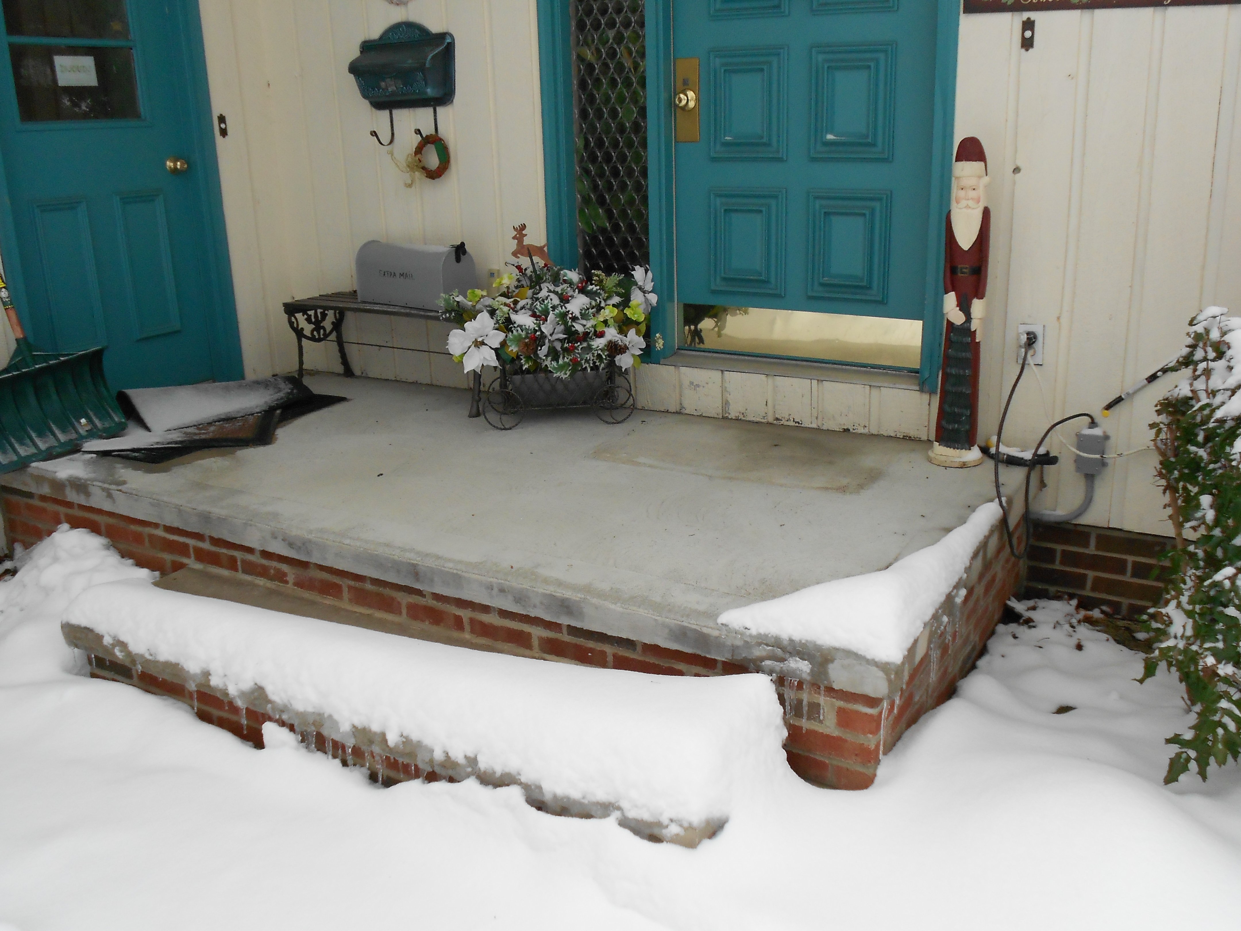 A clear concrete porch landing free of snow during winter, maintained by an installed snow melting system despite surrounding heavy snowfall.