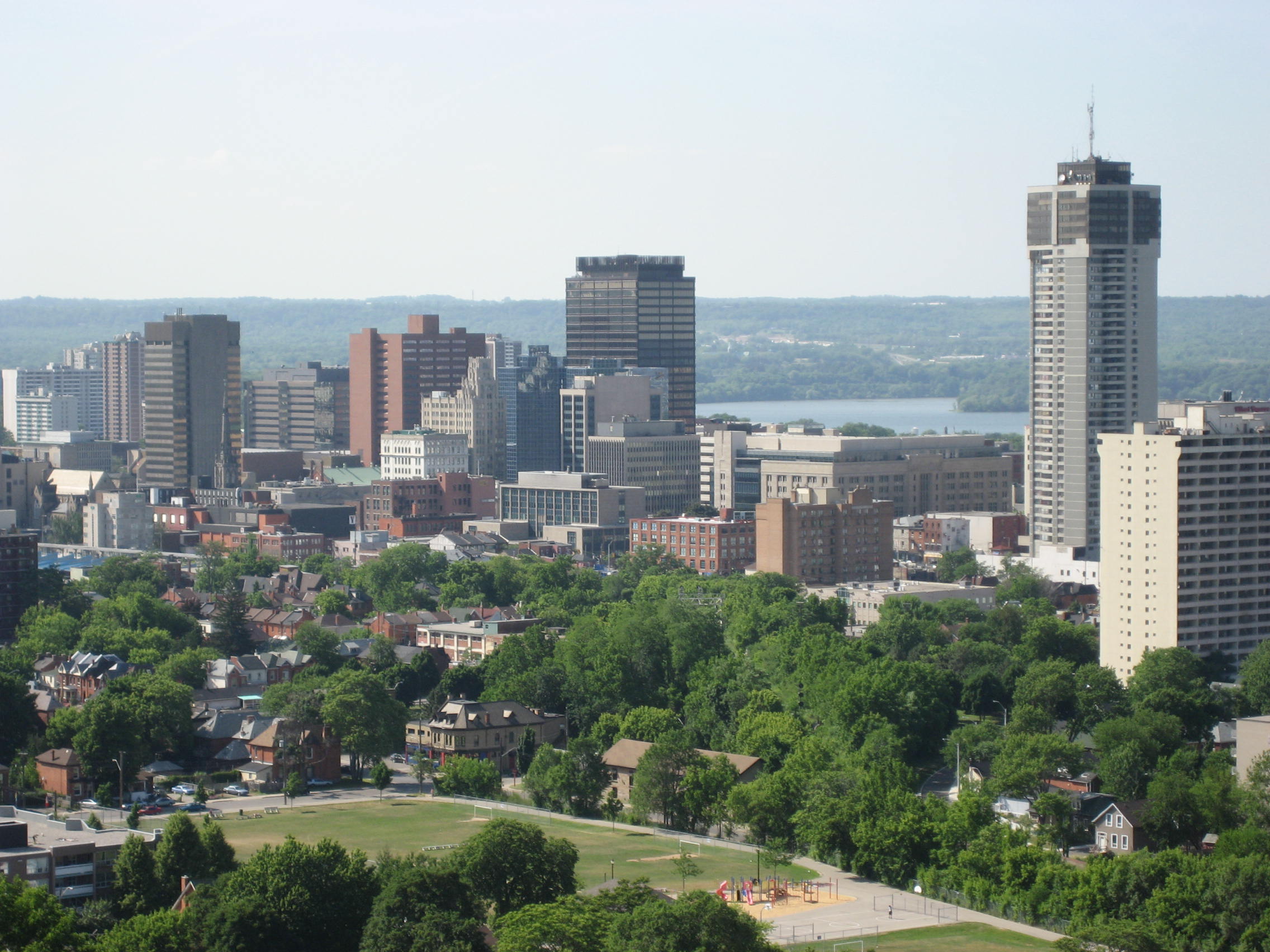 Aerial view of the Hamilton, Ontario skyline featuring urban high-rise buildings, residential neighborhoods, and a public park.