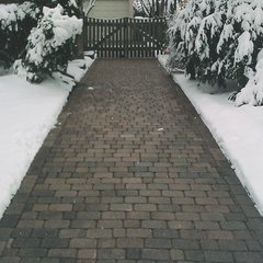 A clear, snow-free paver walkway in winter, maintained by an active electric snow melting system installed beneath the surface.