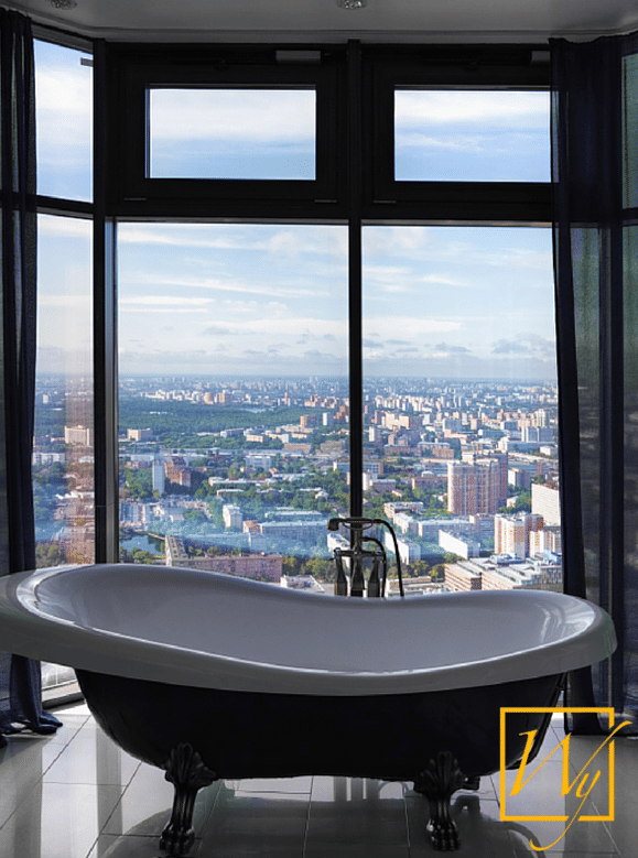Modern high-rise bathroom with light grey tiled flooring concealing an electric radiant floor heating system near a black clawfoot bathtub.