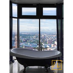 Modern high-rise bathroom with light grey tiled flooring concealing an electric radiant floor heating system near a black clawfoot bathtub.