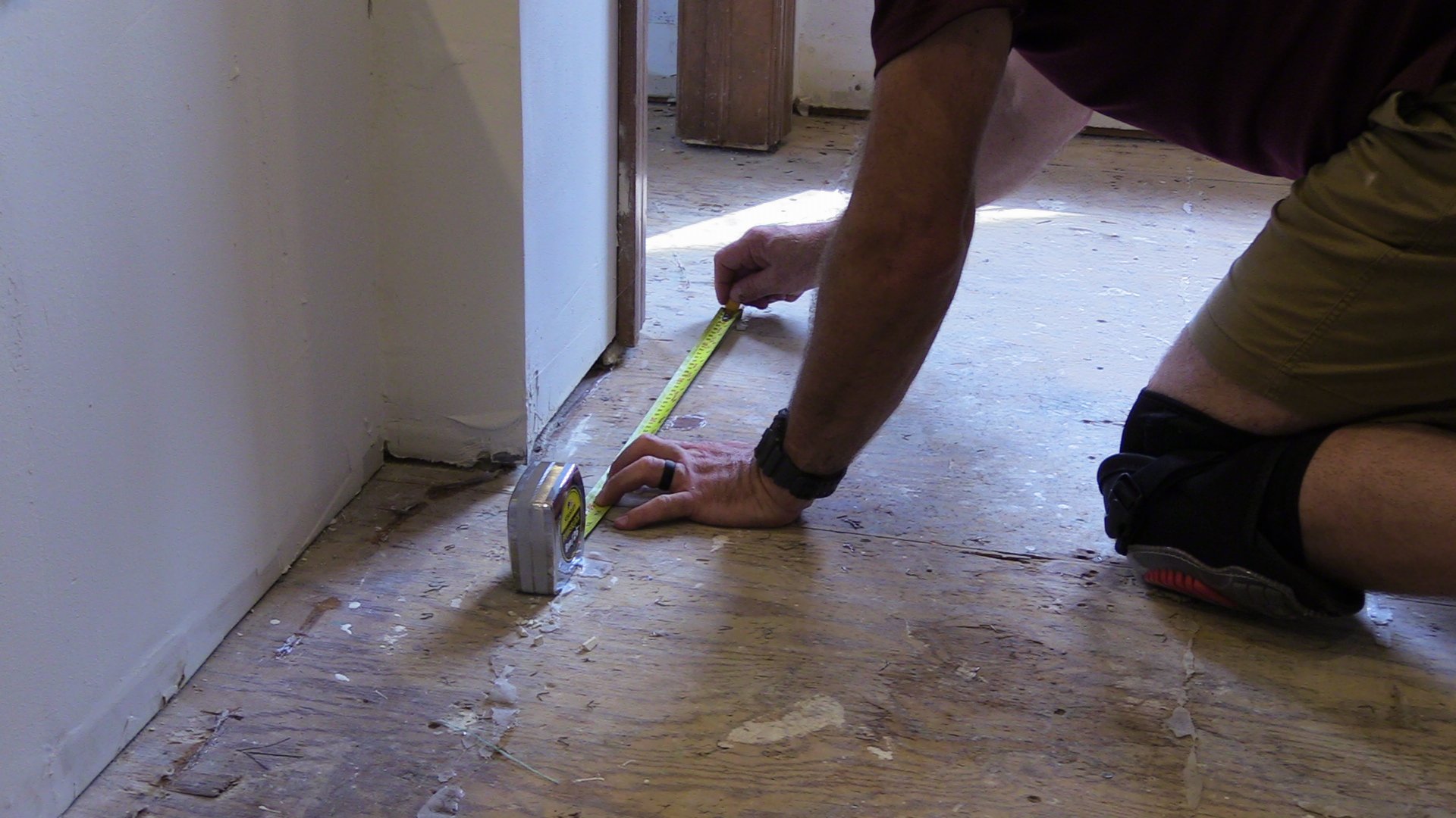 Person measuring the usable floor space with a tape measure and sketching the layout for an electric floor heating installation