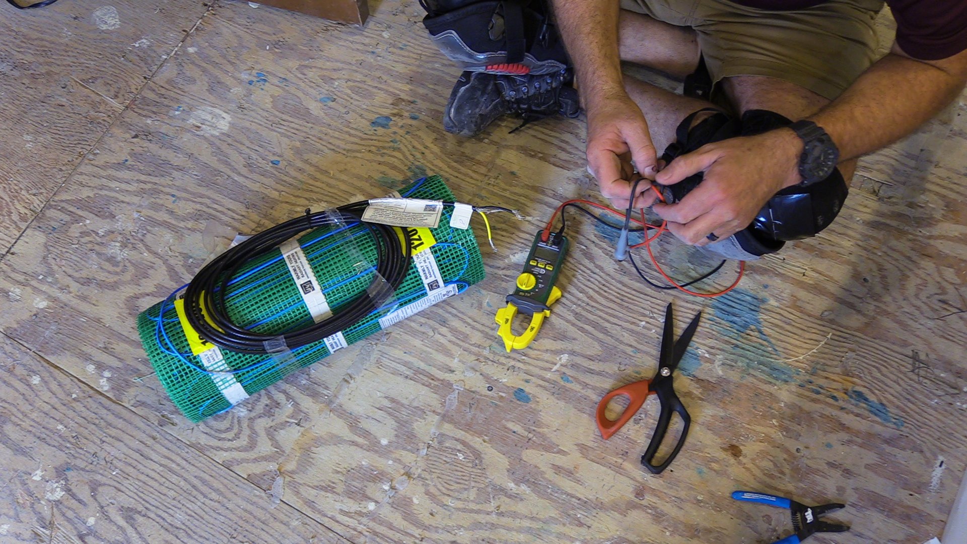 Digital ohmmeter testing a TempZone floor heating mat to confirm electrical continuity before installation