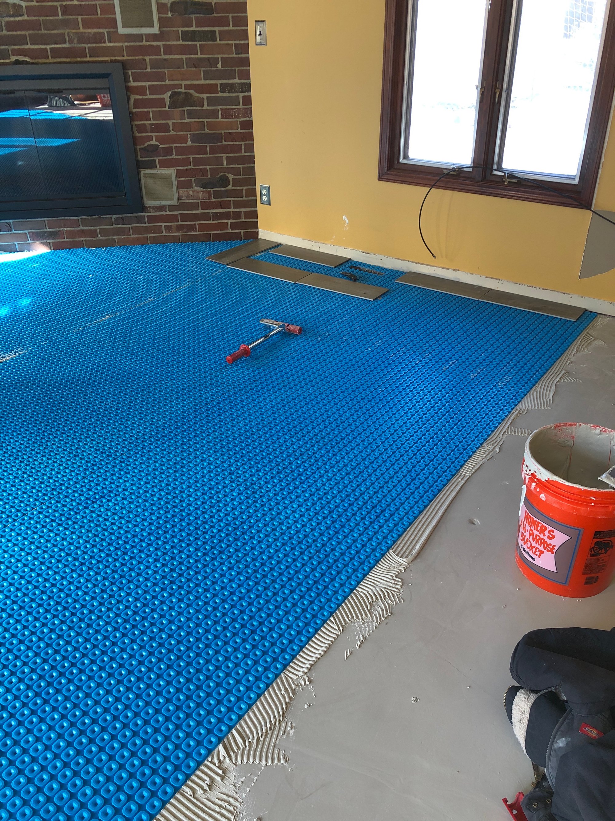 installing uncoupling membrane in living room for heated tile floors