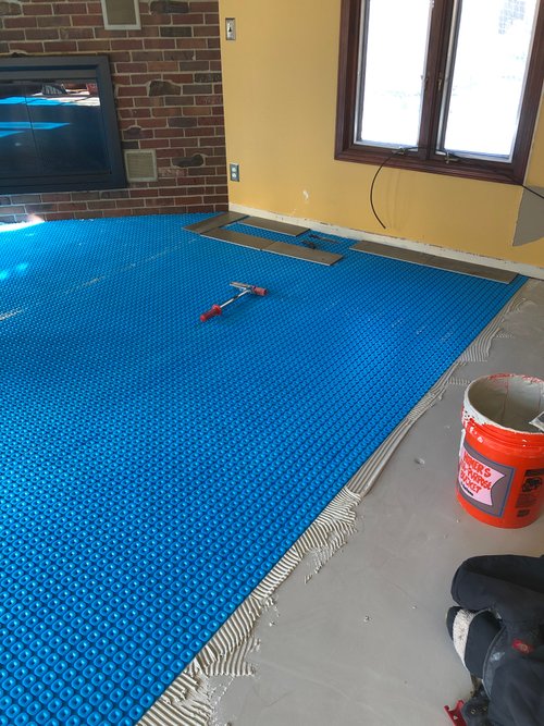 installing uncoupling membrane in living room for heated tile floors