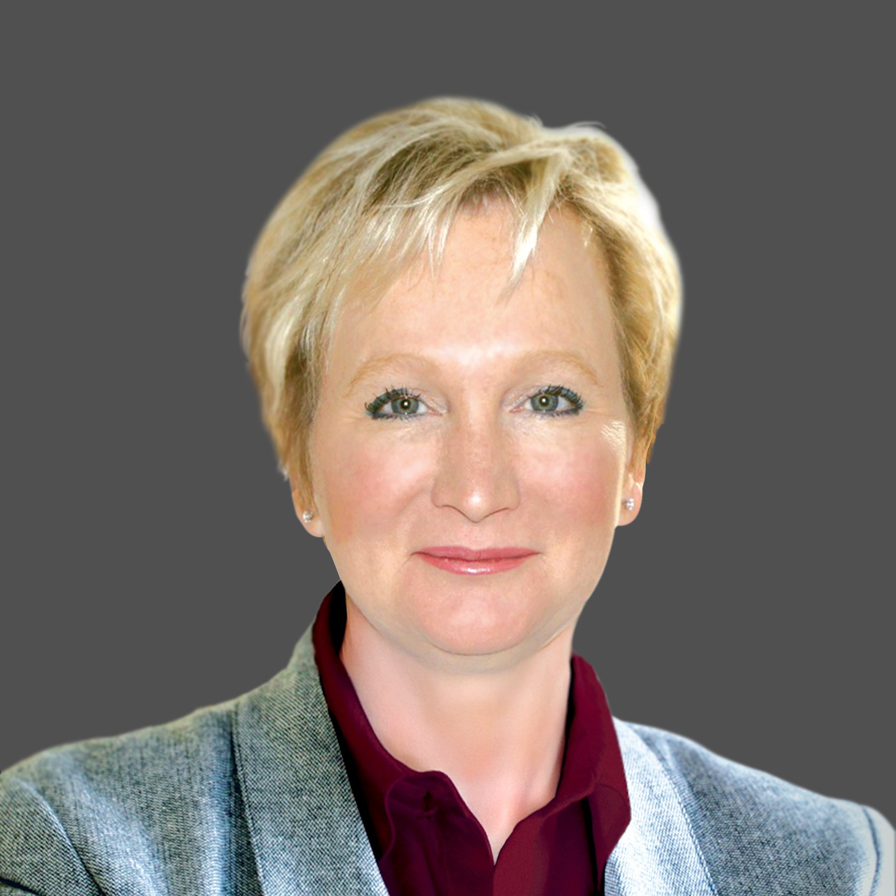 Studio portrait of Julia Billen wearing a maroon collared shirt and grey blazer against a dark grey background.