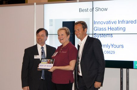 WarmlyYours team receiving a Best of Show award for their innovative infrared glass heating panel at a trade show.