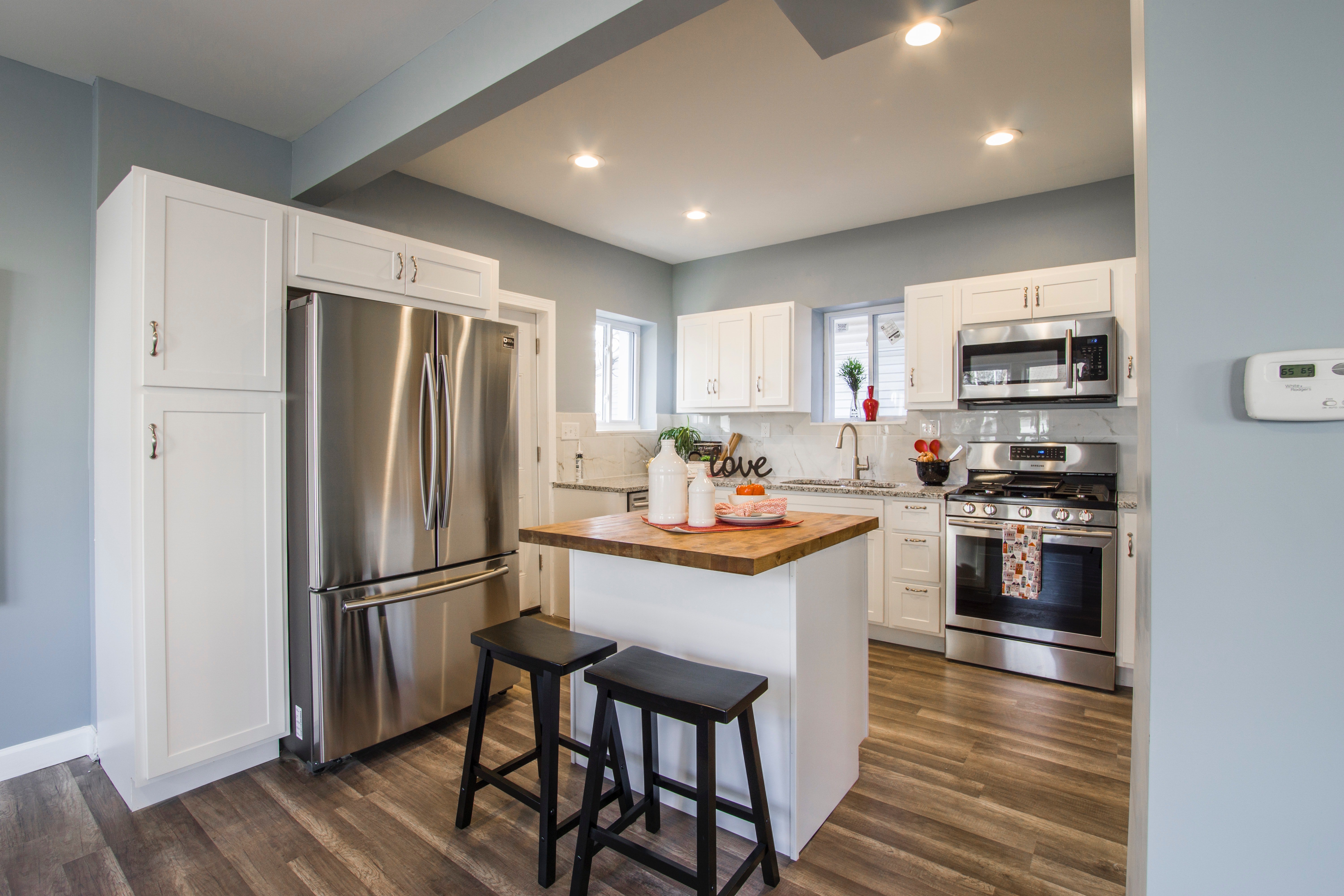 A White-Rodgers digital thermostat mounted on a kitchen wall to control electric radiant floor heating.