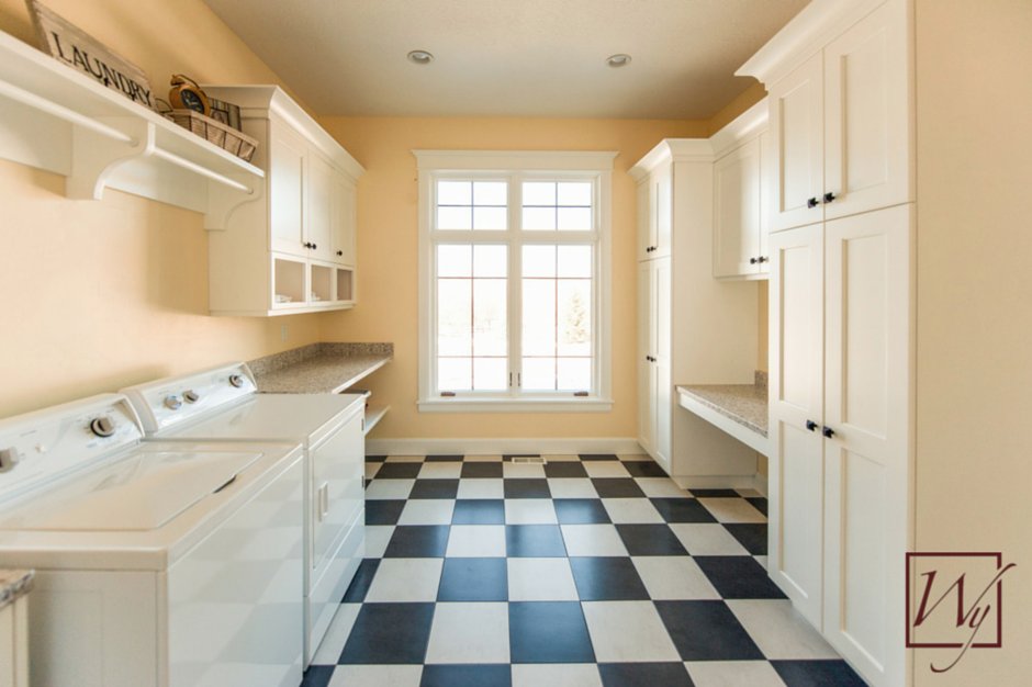 A bright laundry room with checkerboard tile flooring featuring an integrated electric radiant floor heating system.