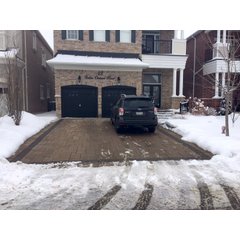 A residential driveway with a snow melting system keeping the stone pavers clear of snow and ice during a winter storm.