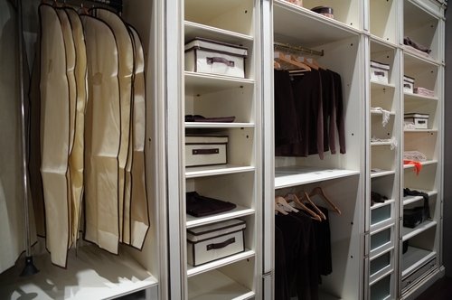 A well-organized walk-in closet featuring open shelving, hanging clothing sections, and pull-out drawers for storage.