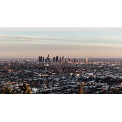 Panoramic view of the Los Angeles skyline and metropolitan basin under a pastel sunset.
