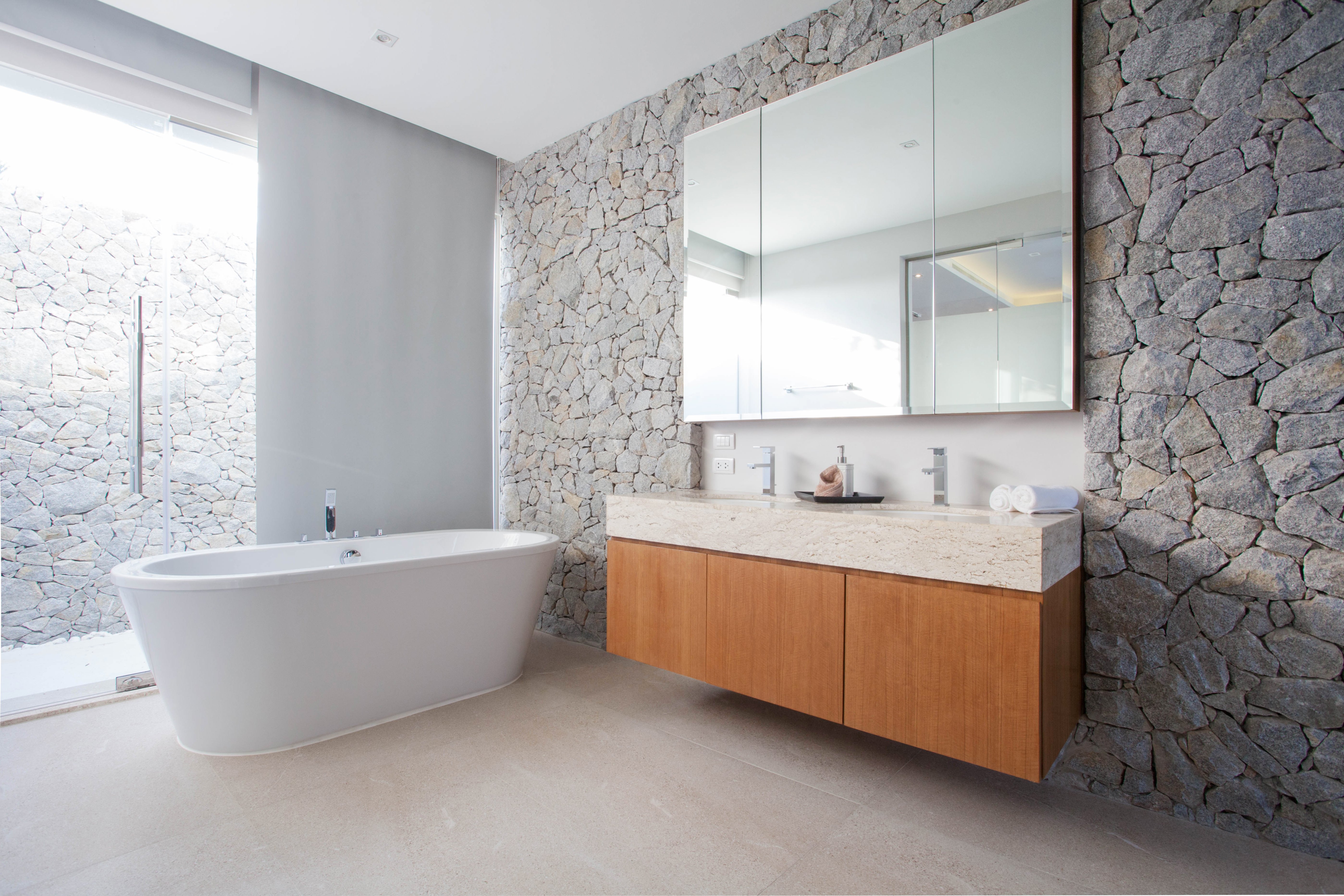 A luxury bathroom featuring a freestanding oval bathtub, floating double vanity, and tile flooring suitable for electric radiant floor heating.
