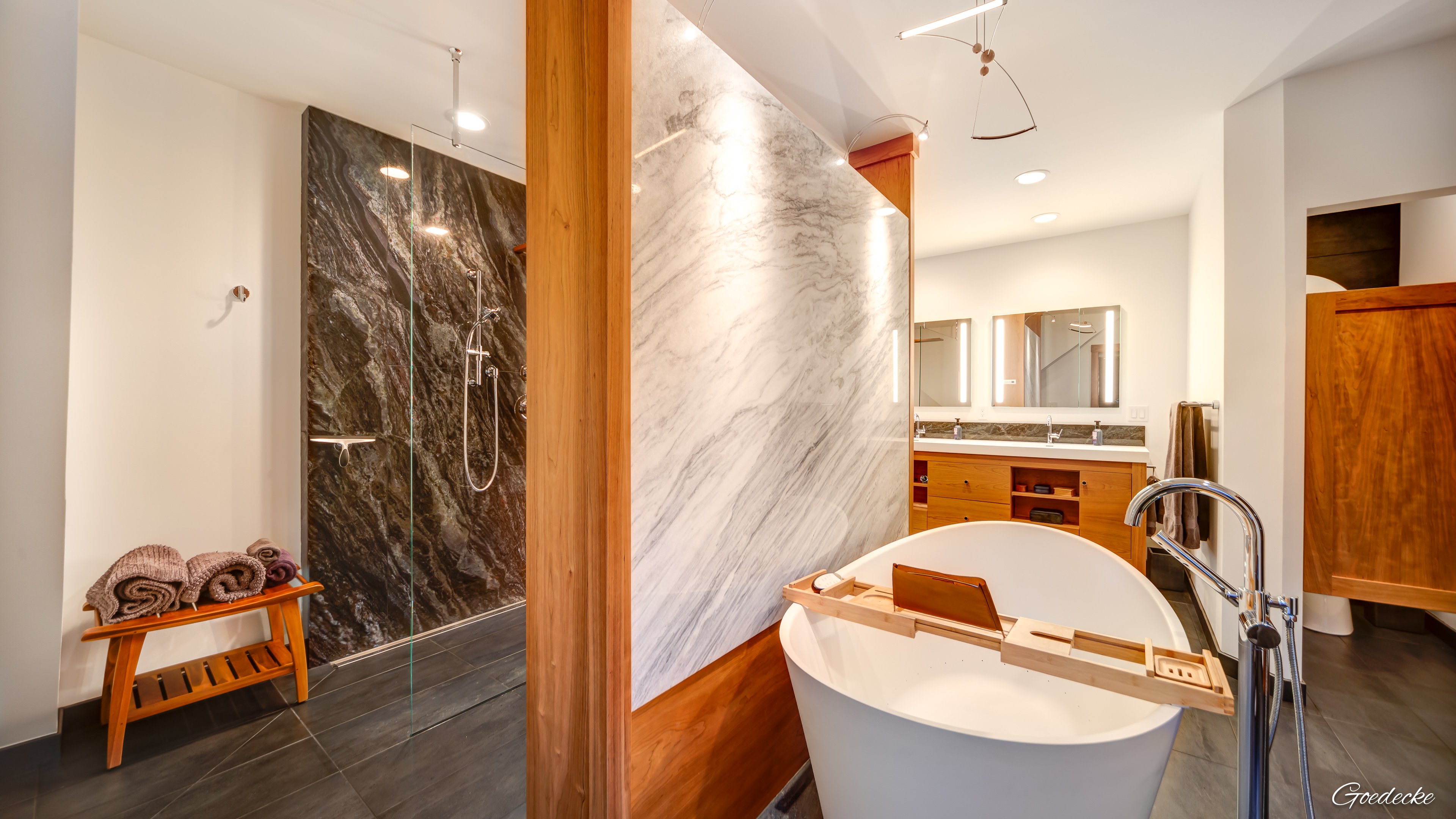 Freestanding bathtub next to a custom stone wall featuring electric radiant underfloor heating.