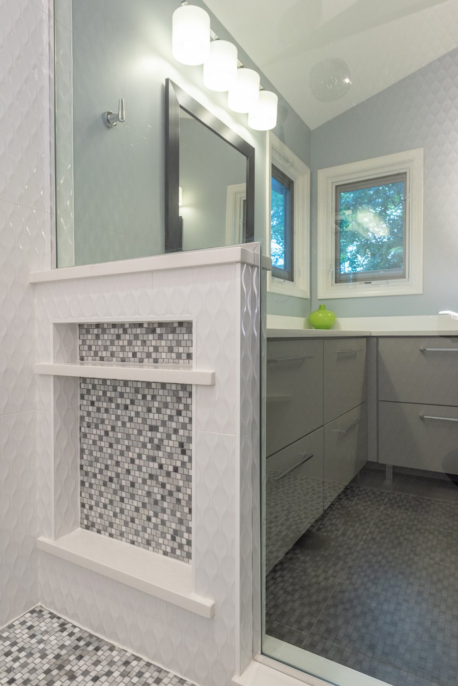 Modern blue master bathroom featuring tiled shower accent wall and heated tile floor surface.