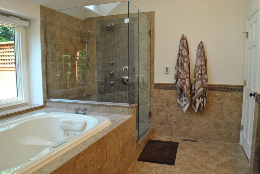 Spacious master bathroom with beige tile flooring, a soaking tub, and a glass-enclosed walk-in shower.
