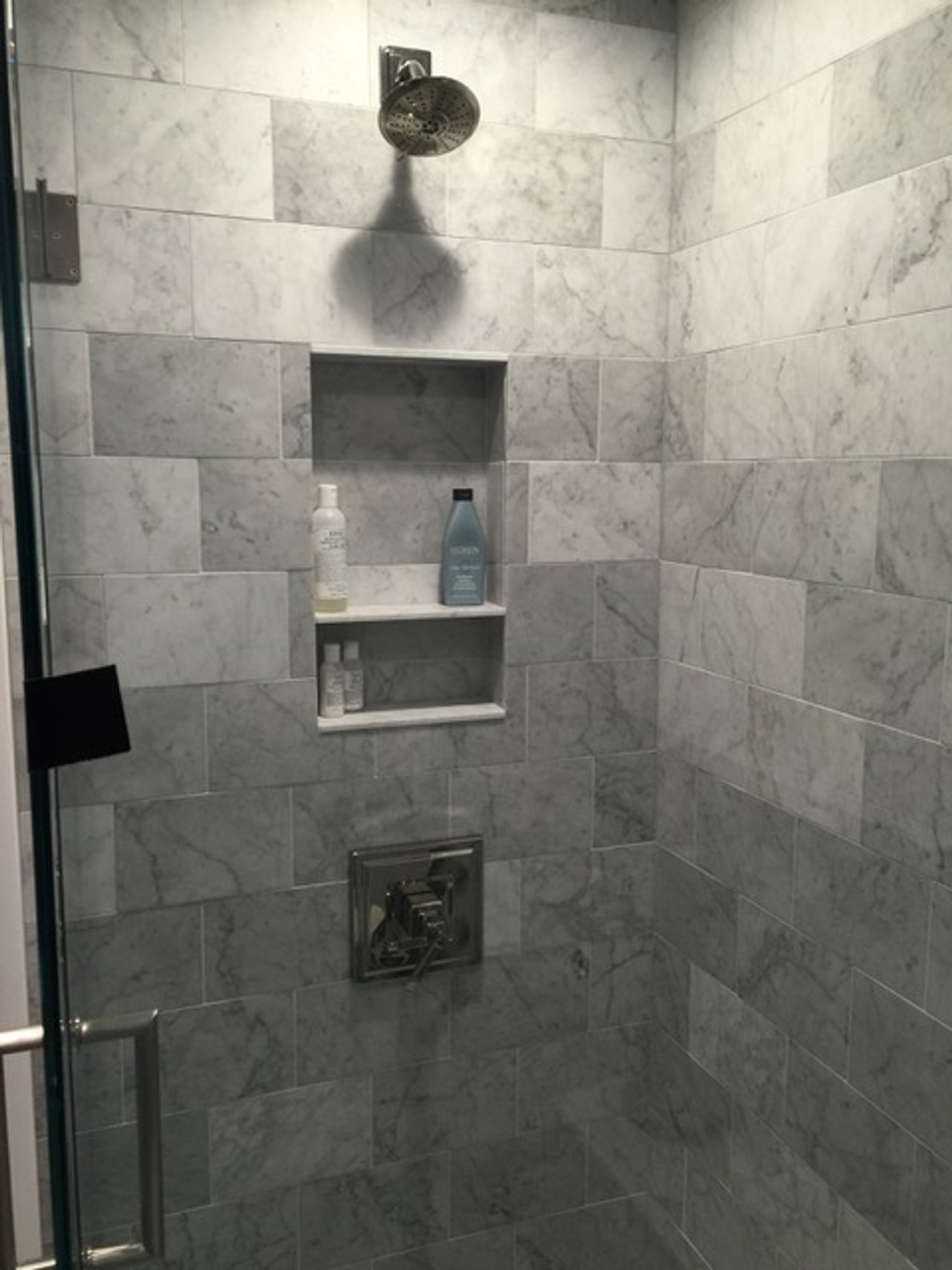 Modern marble tile walk-in shower with built-in niche wall in a luxury radiant floor heating remodel project.