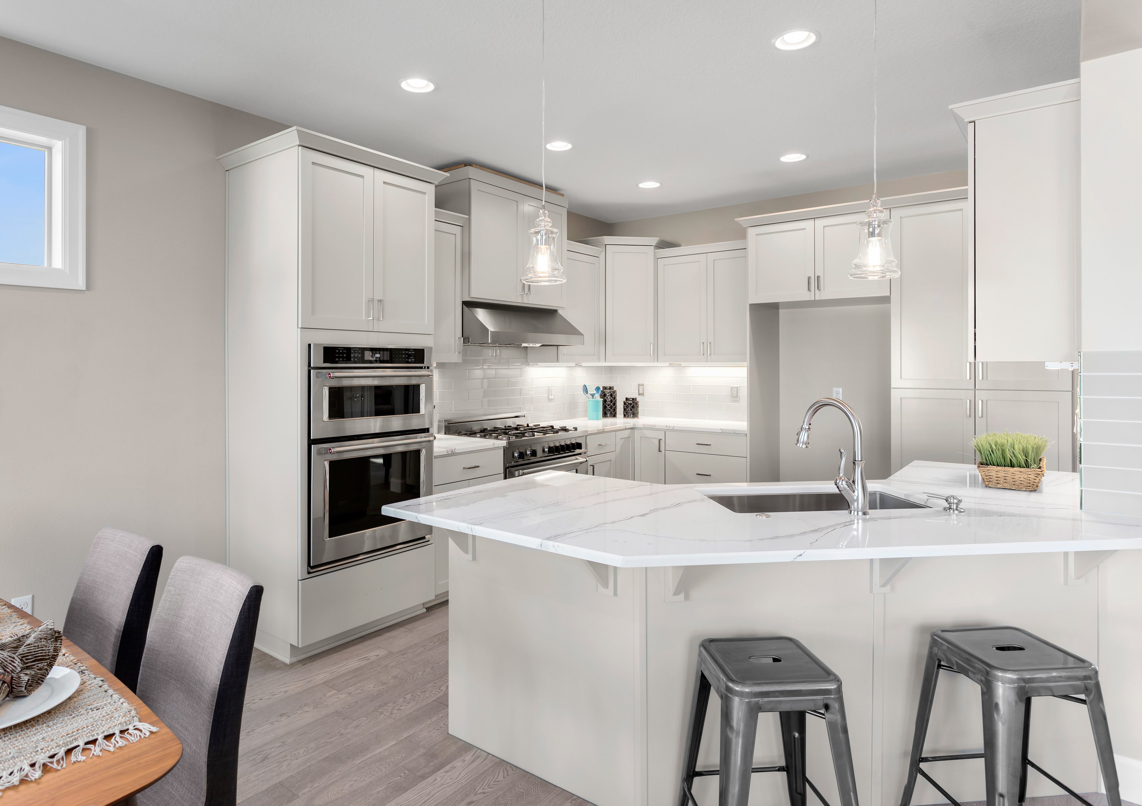 Modern open-concept kitchen with light-toned wood-look plank flooring, white marble countertops, and stainless steel appliances.
