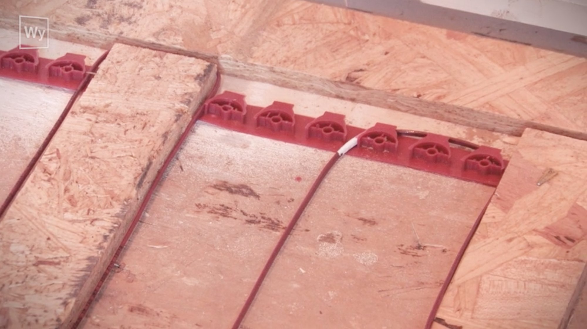 Nailed hardwood floor heating installation with halfway mark indicated on cable