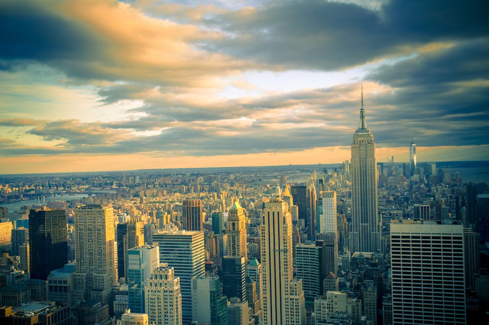 Aerial view of the New York City skyline featuring the Empire State Building illuminated by golden sunset light.