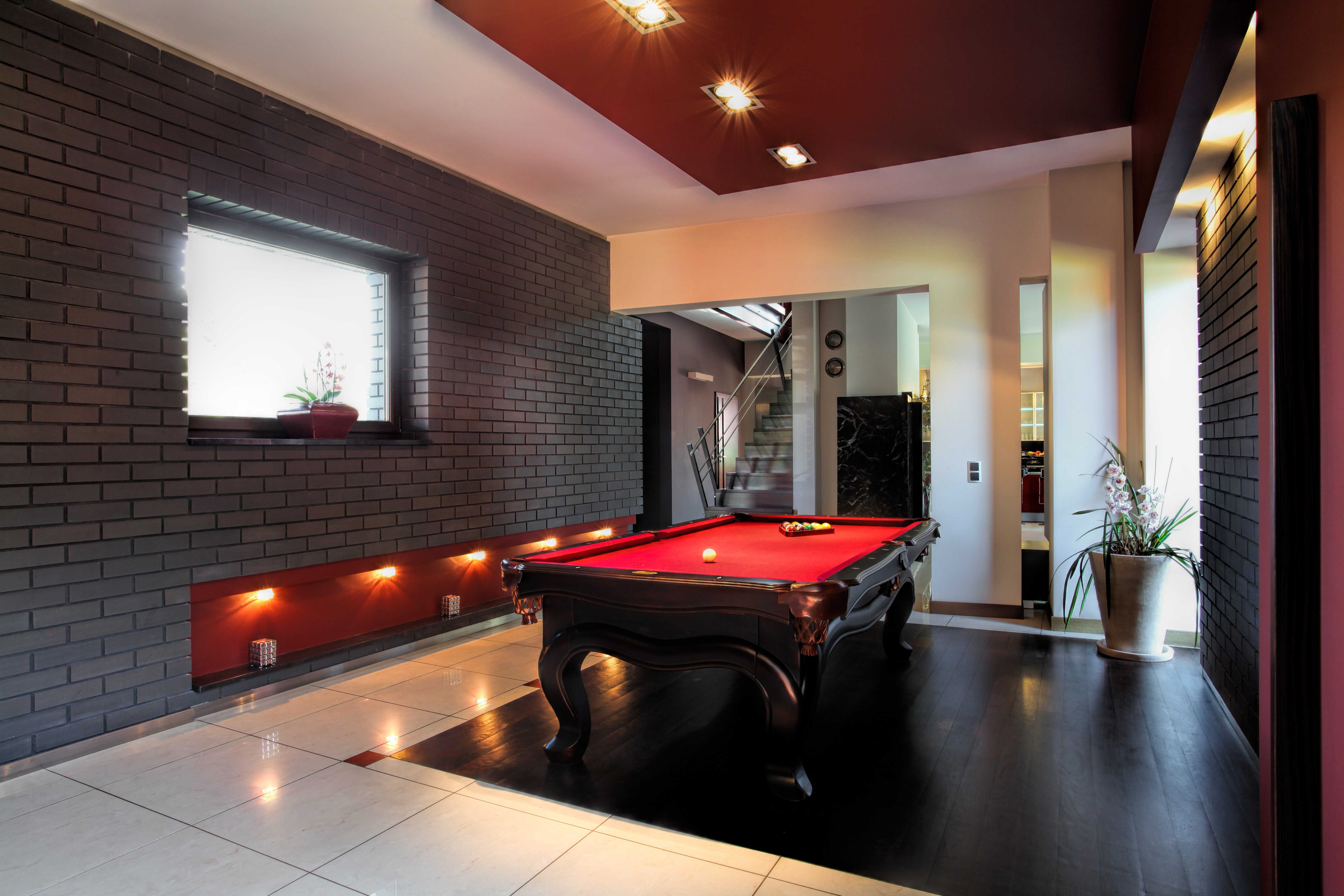 Electric radiant floor heating installed beneath light ceramic tiles in a modern basement recreation room with a billiard table.