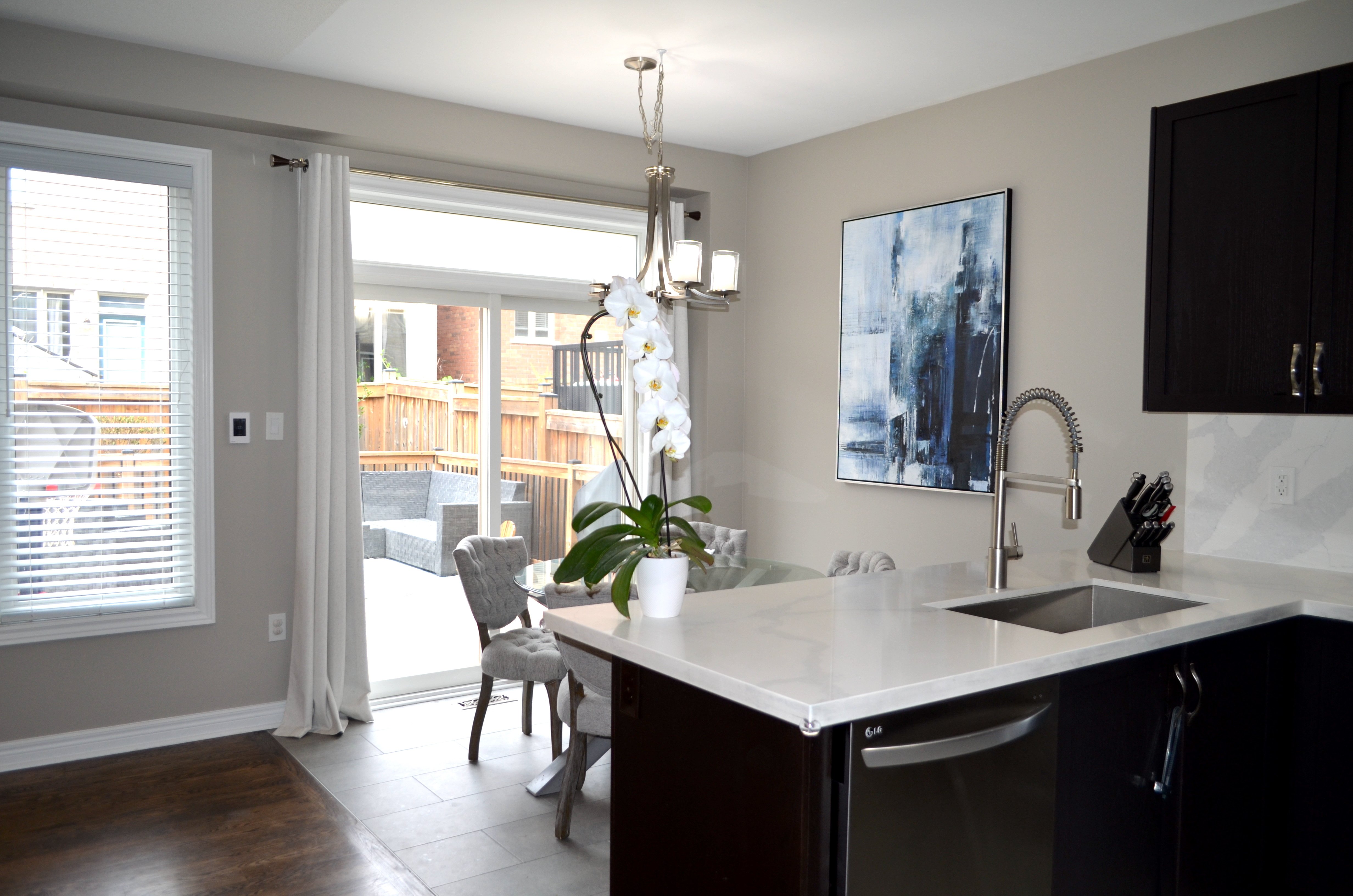 A wall-mounted thermostat controlling an electric radiant floor heating system in a kitchen and dining area with tiled flooring.