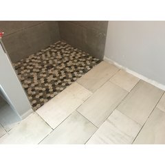 A bathroom floor and curbless shower installation featuring hexagonal mosaic tiles and large format stone-look tiles over a Prodeso membrane.
